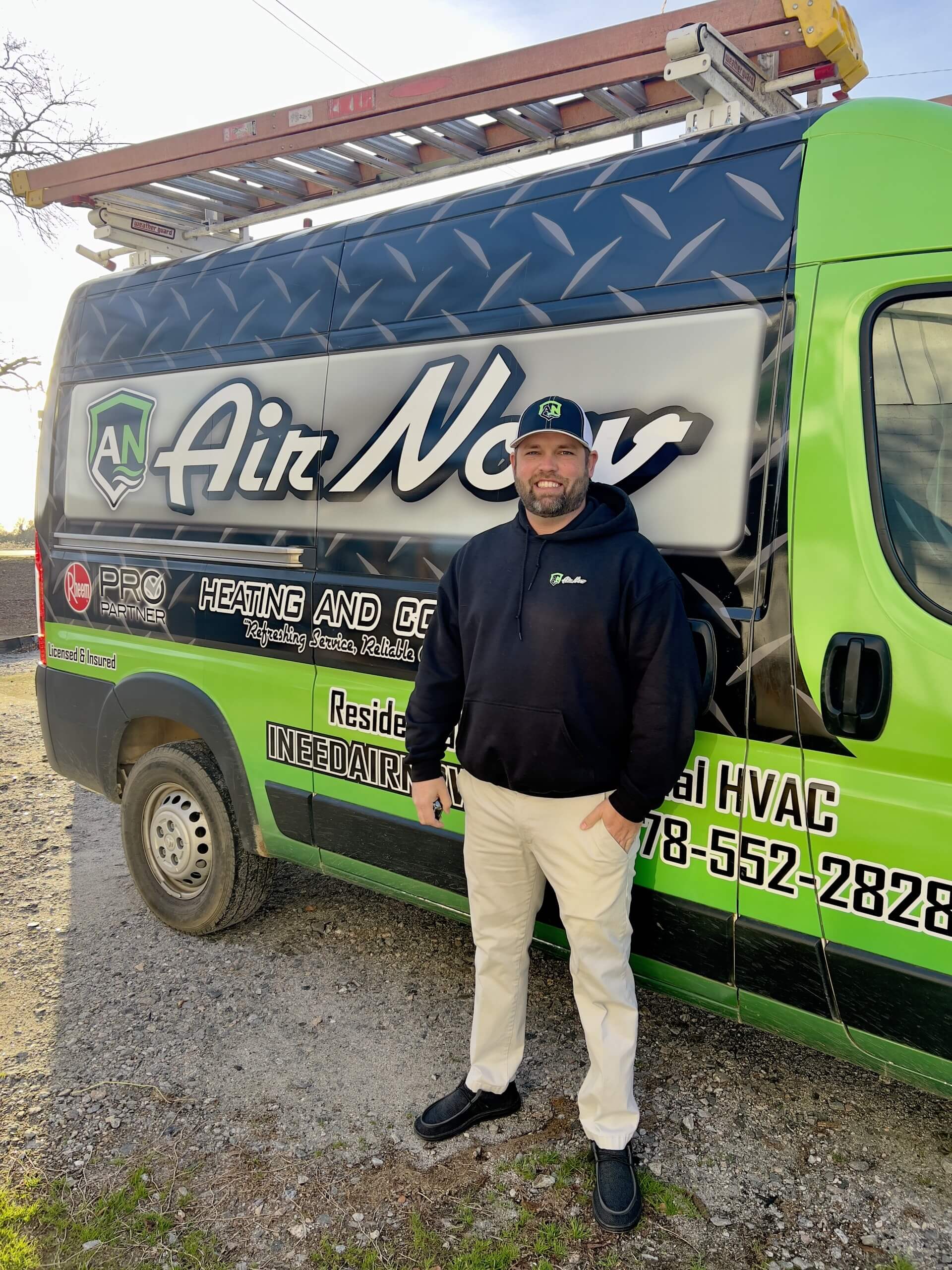 An AirNow technician posing with his truck in Evans